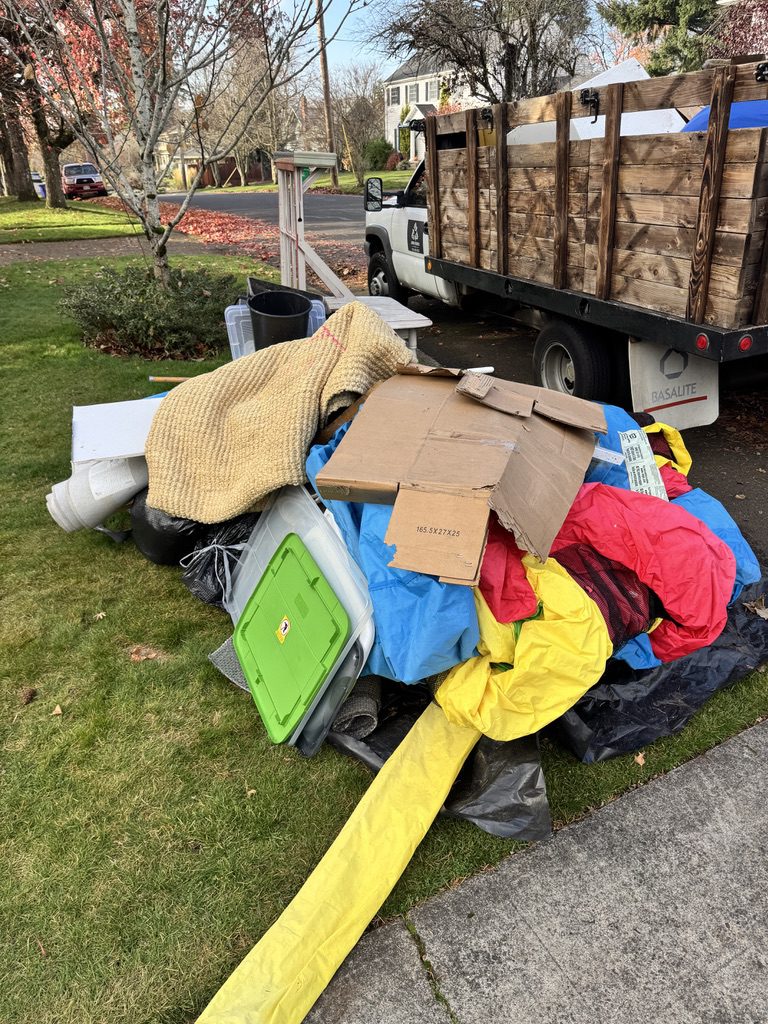 Pile of household junk ready for removal next to Junk Hubris truck in Portland