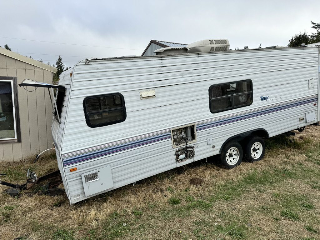 Damaged travel trailer with bent tongue ready for professional removal