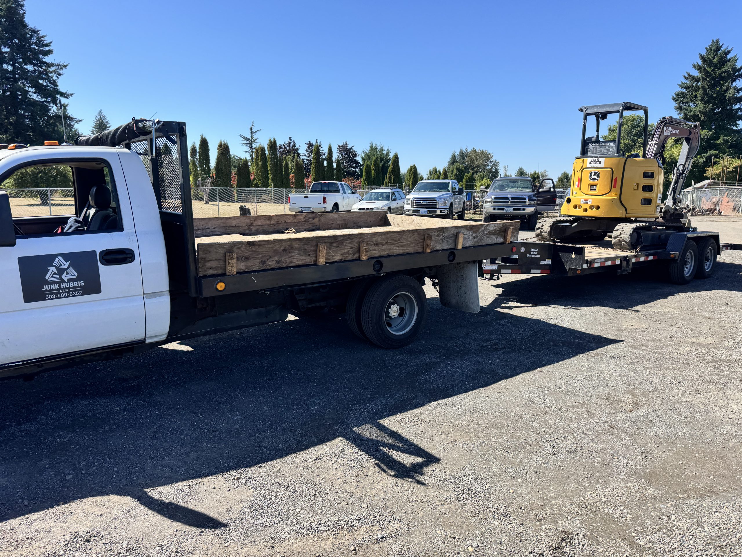 Junk Hubris flatbed truck with excavator ready for construction debris removal in Portland